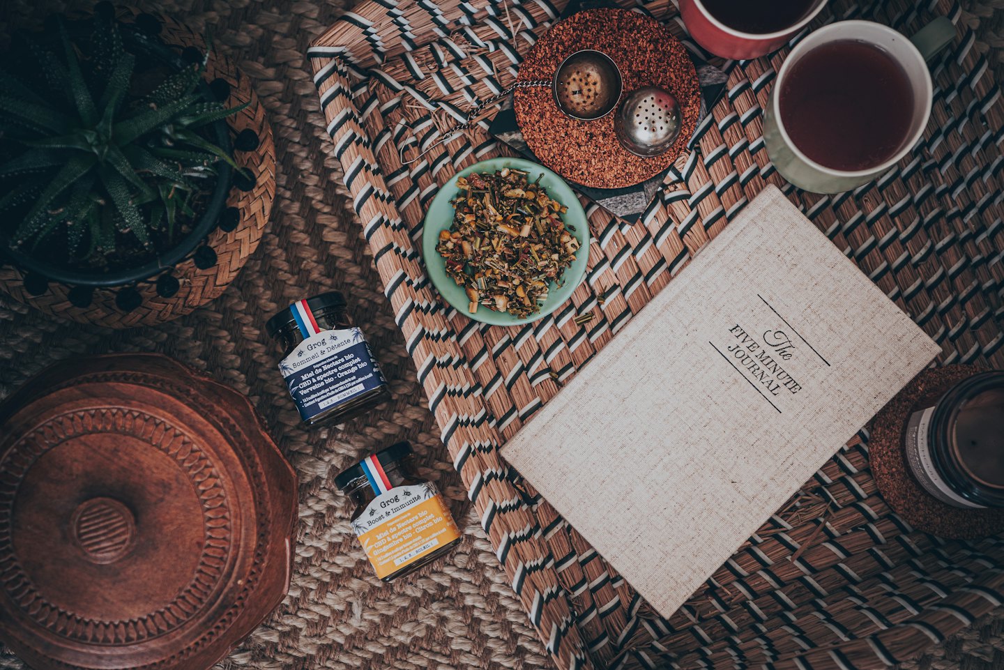 Wellness items arranged on a woven mat for a relaxing tea break.