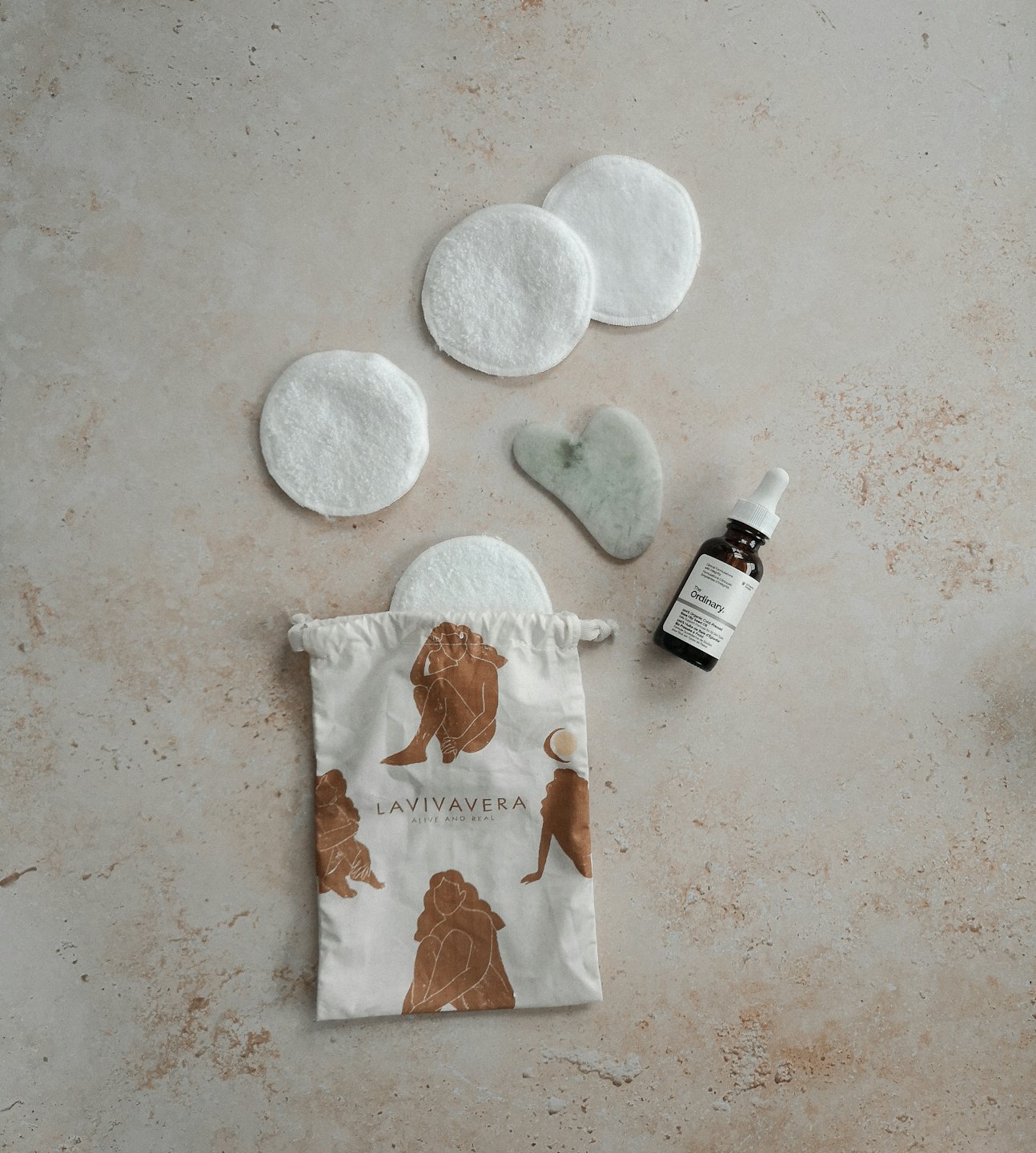 Skincare products including a gua sha and serum bottle laid out.